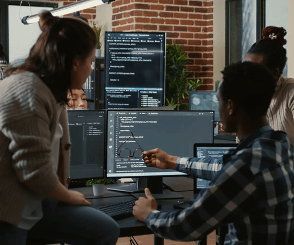 3 people reviewing code on a computer