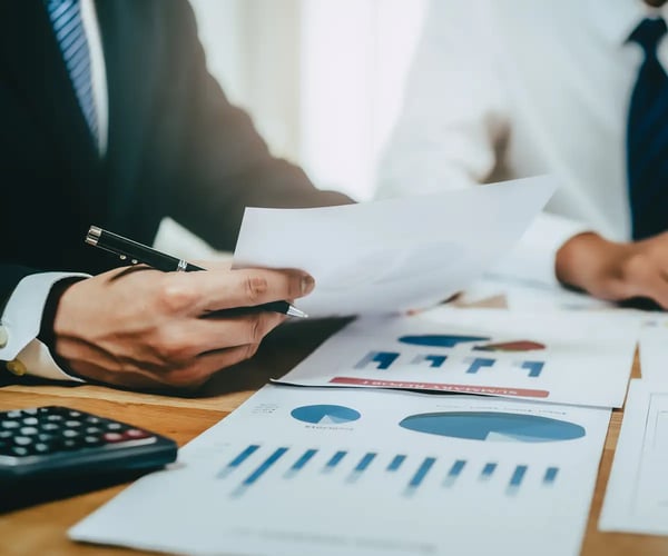 Person holding a piece of paper over a desk of papers