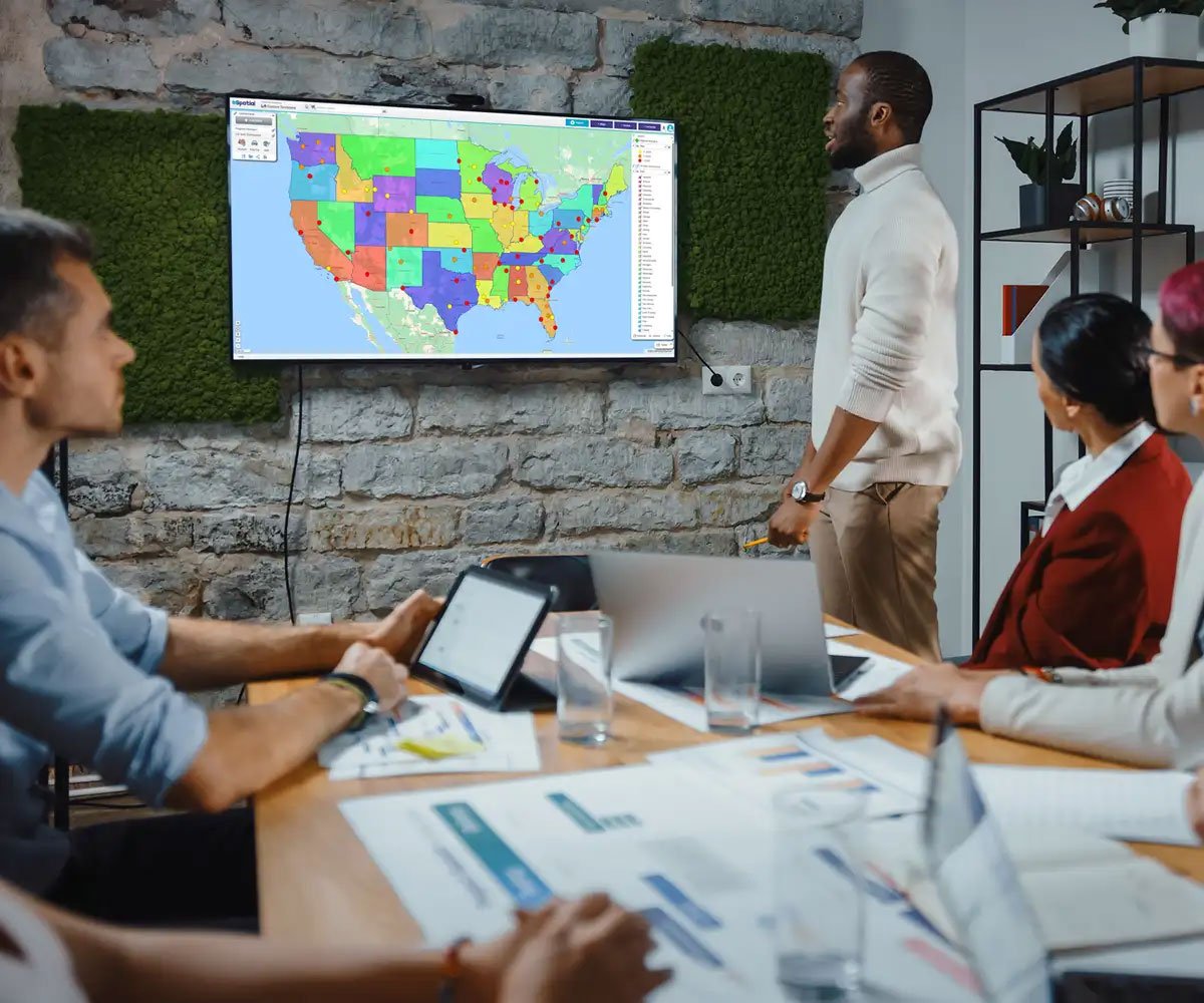 Team meeting reviewing territory map on a screen